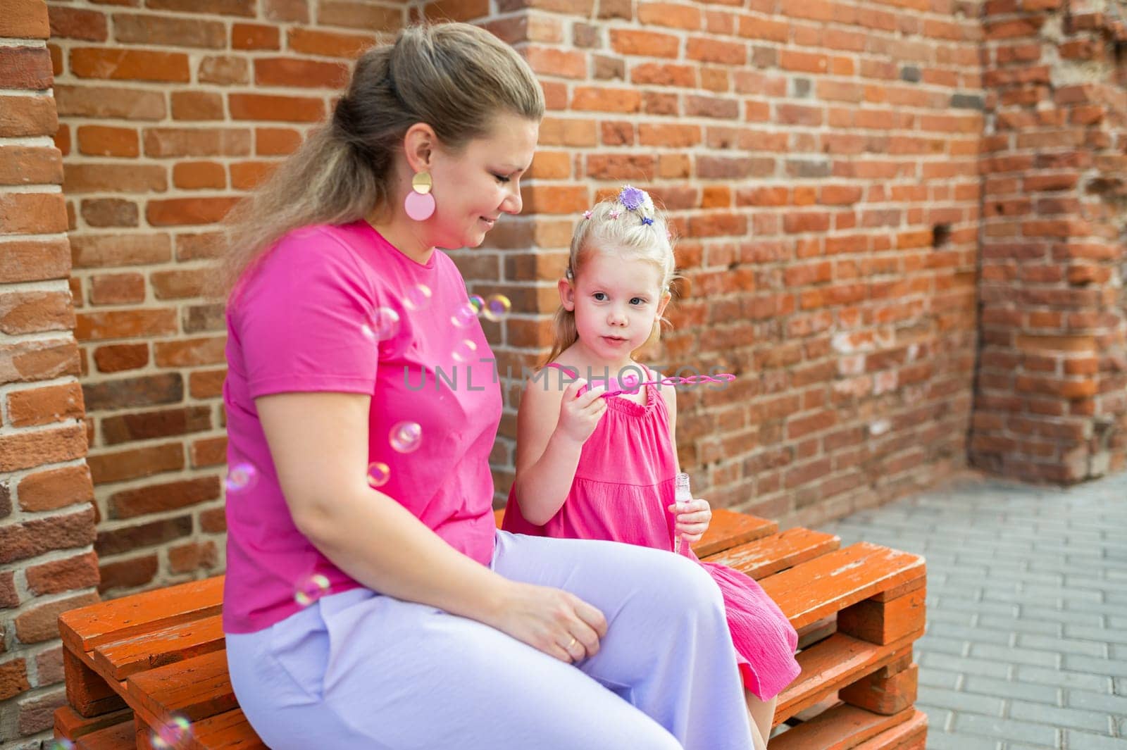 Deaf child with cochlear implant for hearing audio and aid for impairment having fun and laughs with mother outdoor in summer. Sound fitting device to help with communication listening and interaction. Inclusion and people with disability concept. by Satura86