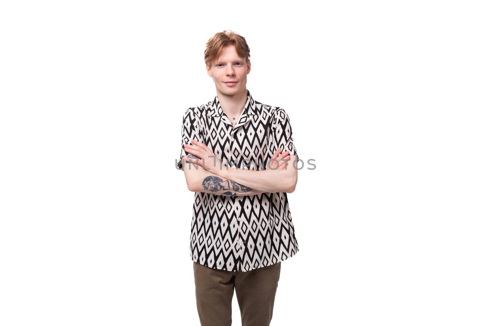 young focused caucasian man with red hair with a tattoo dressed in a summer black and white shirt on a background with copy space.