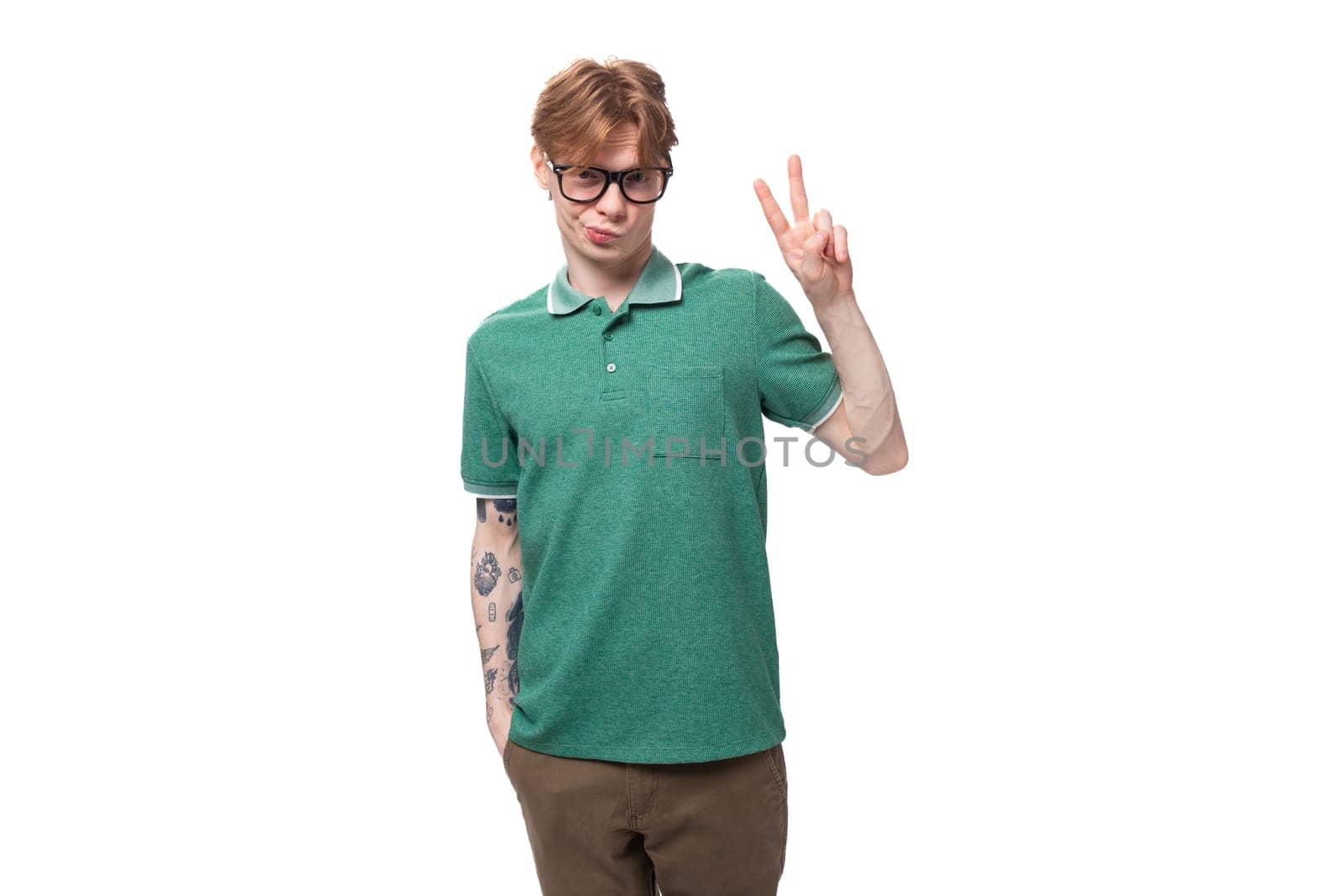 young stylish cheerful european guy with red hair with a tattoo on his forearm wears a green t-shirt by TRMK