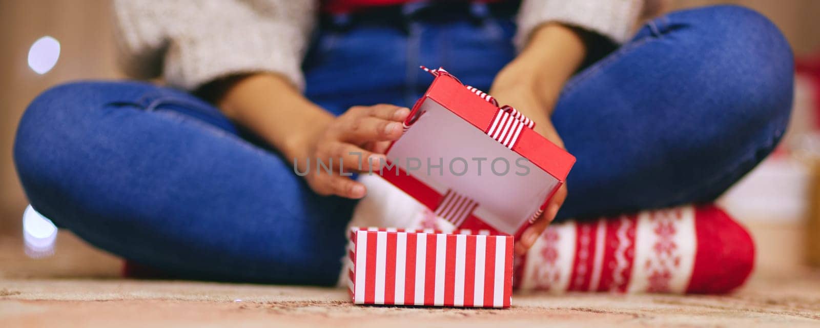 Christmas, unboxing and present in hands of person on holiday or giving a gift on vacation. Home, celebration and ribbon on box with surprise, giveaway or open offering closeup on xmas morning.