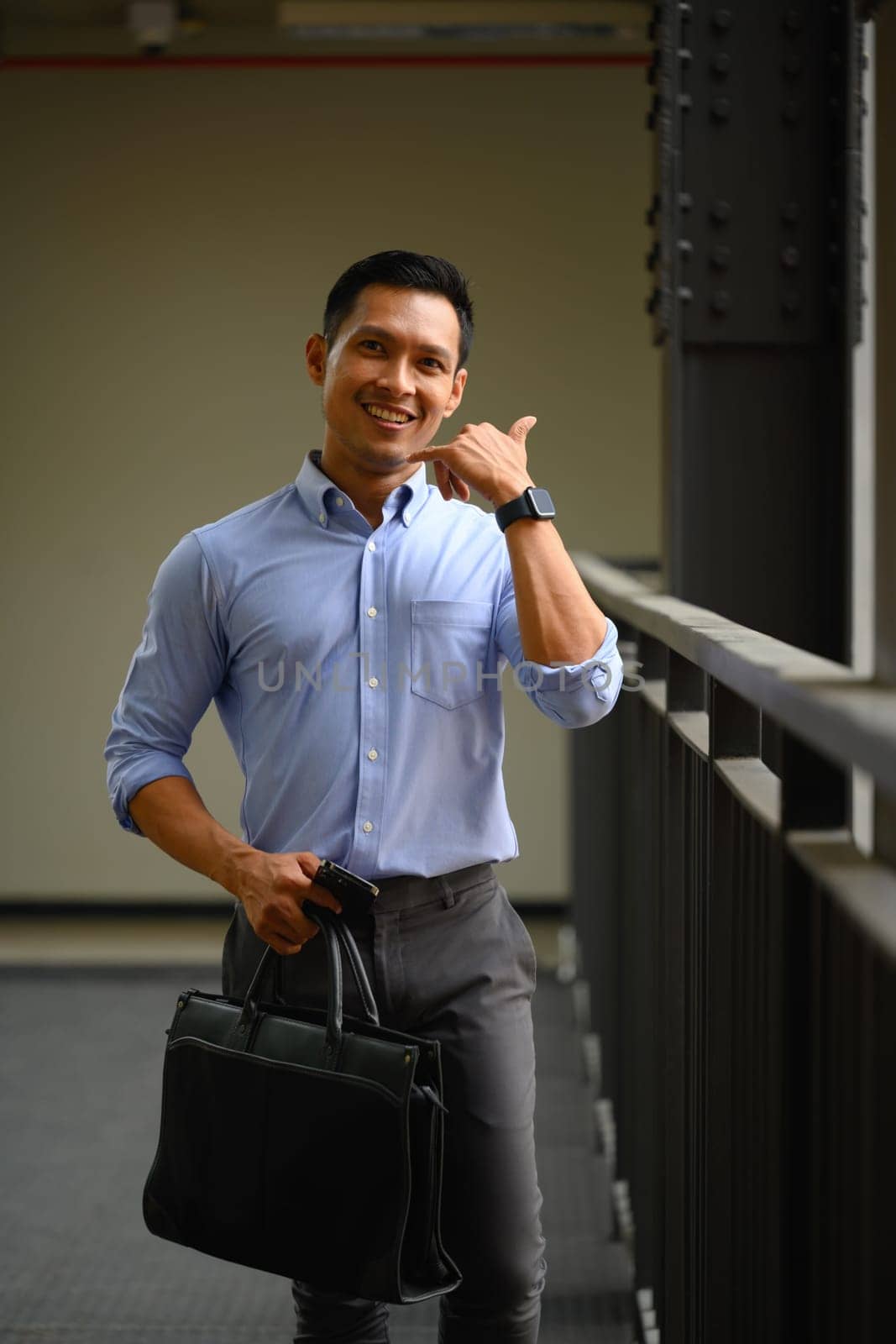 Portrait of handsome businessman making a hand gesture to call him and smiling at camera by prathanchorruangsak