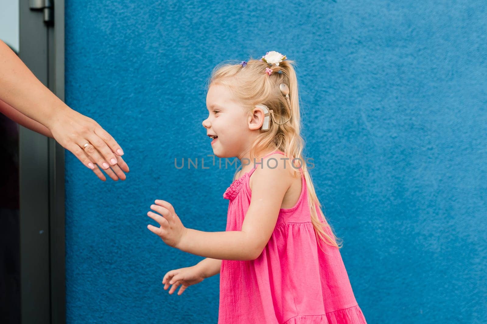 Funny baby with cochlear implant walks outdoor. Hearing aid and medicine innovating technology concept. Diversity and Inclusion and people with disability concept. by Satura86