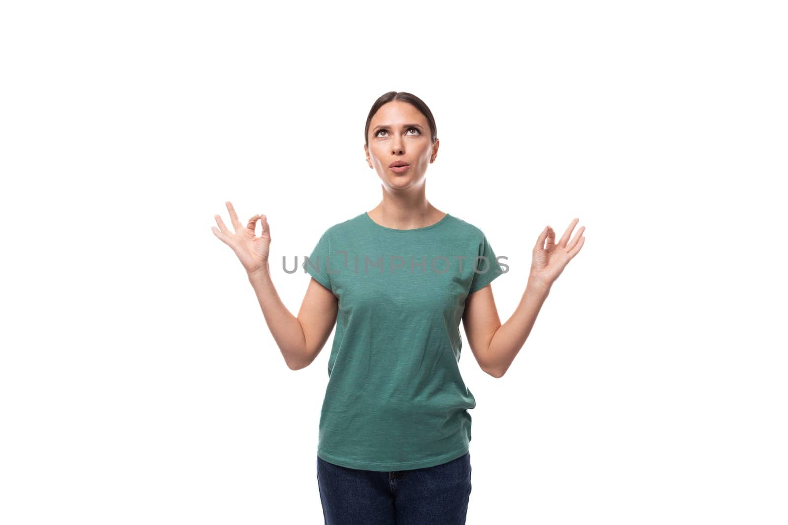 well-groomed slim young brunette woman dressed in a green t-shirt meditates on a white background.