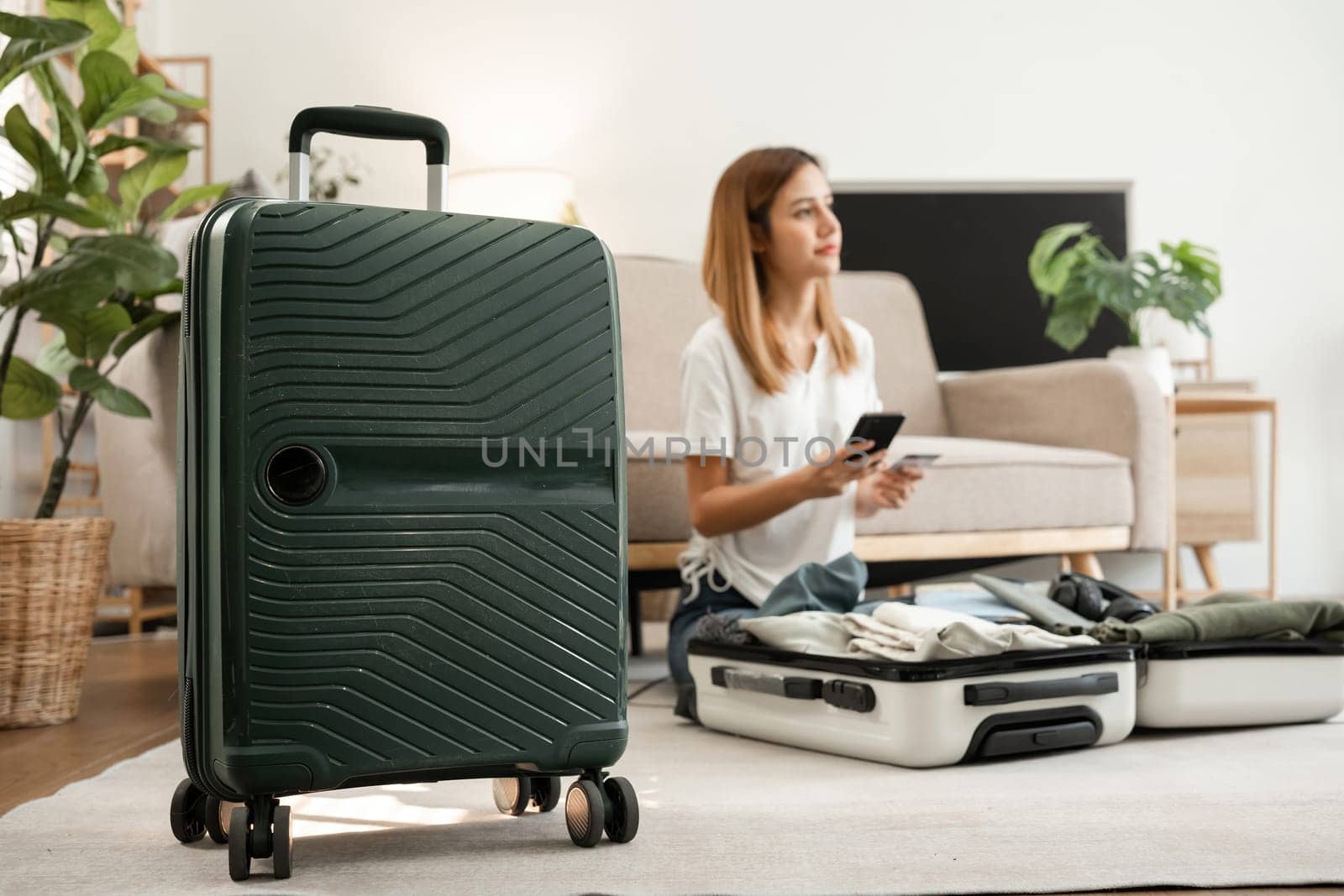A young woman plans a trip, buys a plane ticket online and pays with a credit card through online banking. While preparing your luggage by wichayada
