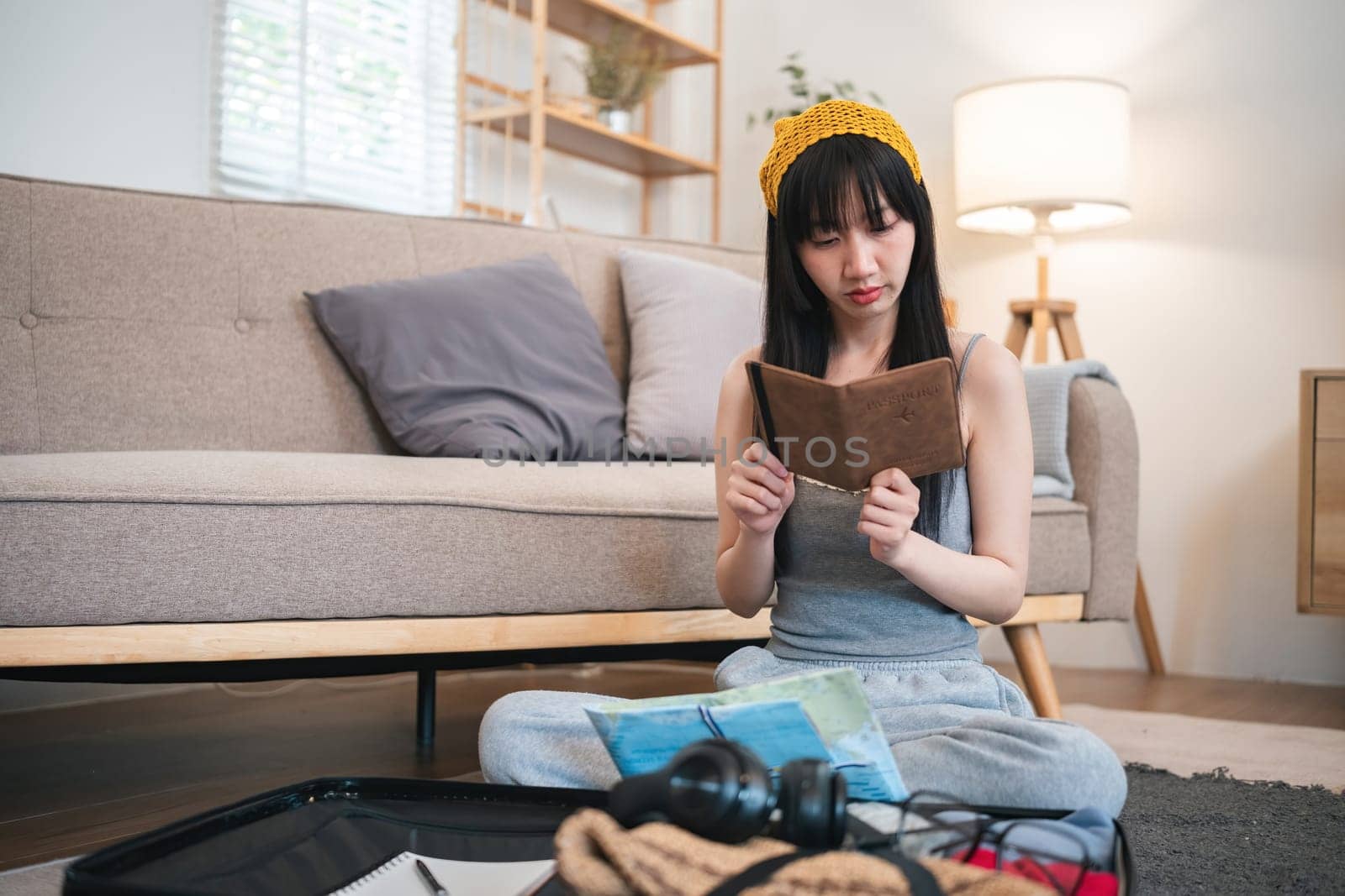 Beautiful young women checks list of items and clothes to pack in her suitcase for a holiday trip. by wichayada