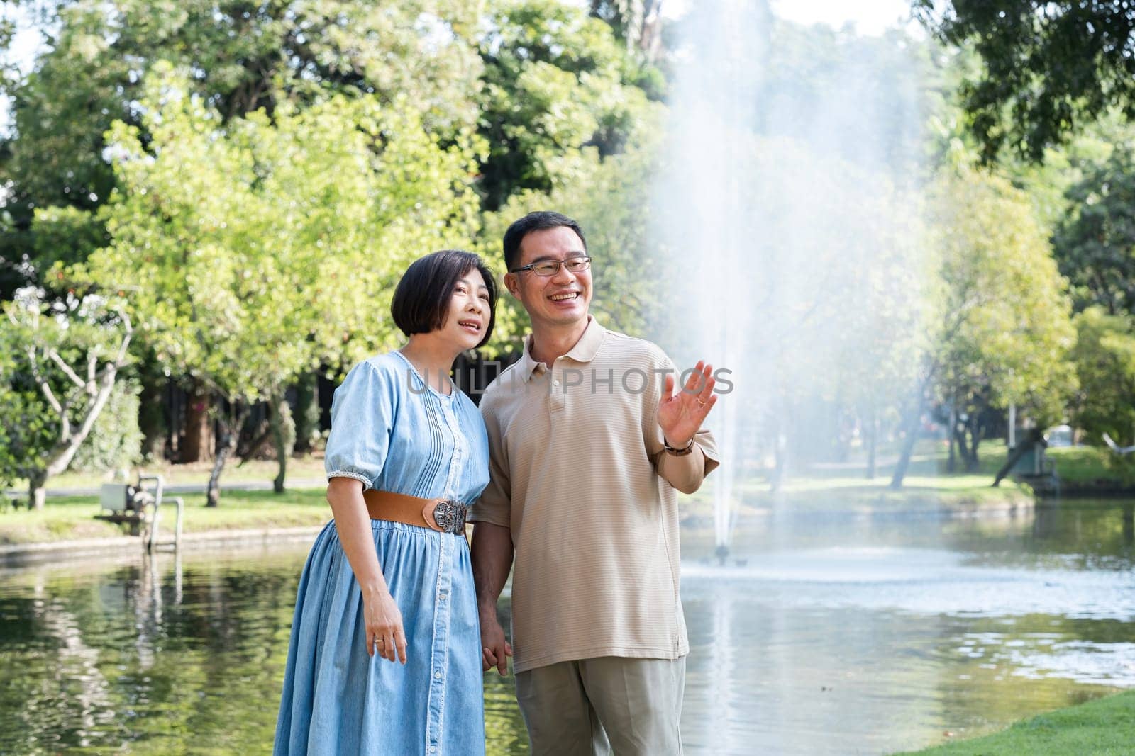 A retired couple walks outside together in the park on a relaxing vacation..