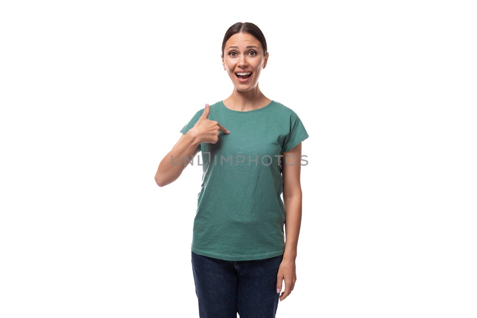 young slender european woman with ponytail hairstyle dressed in green t-shirt draws attention to advertising.