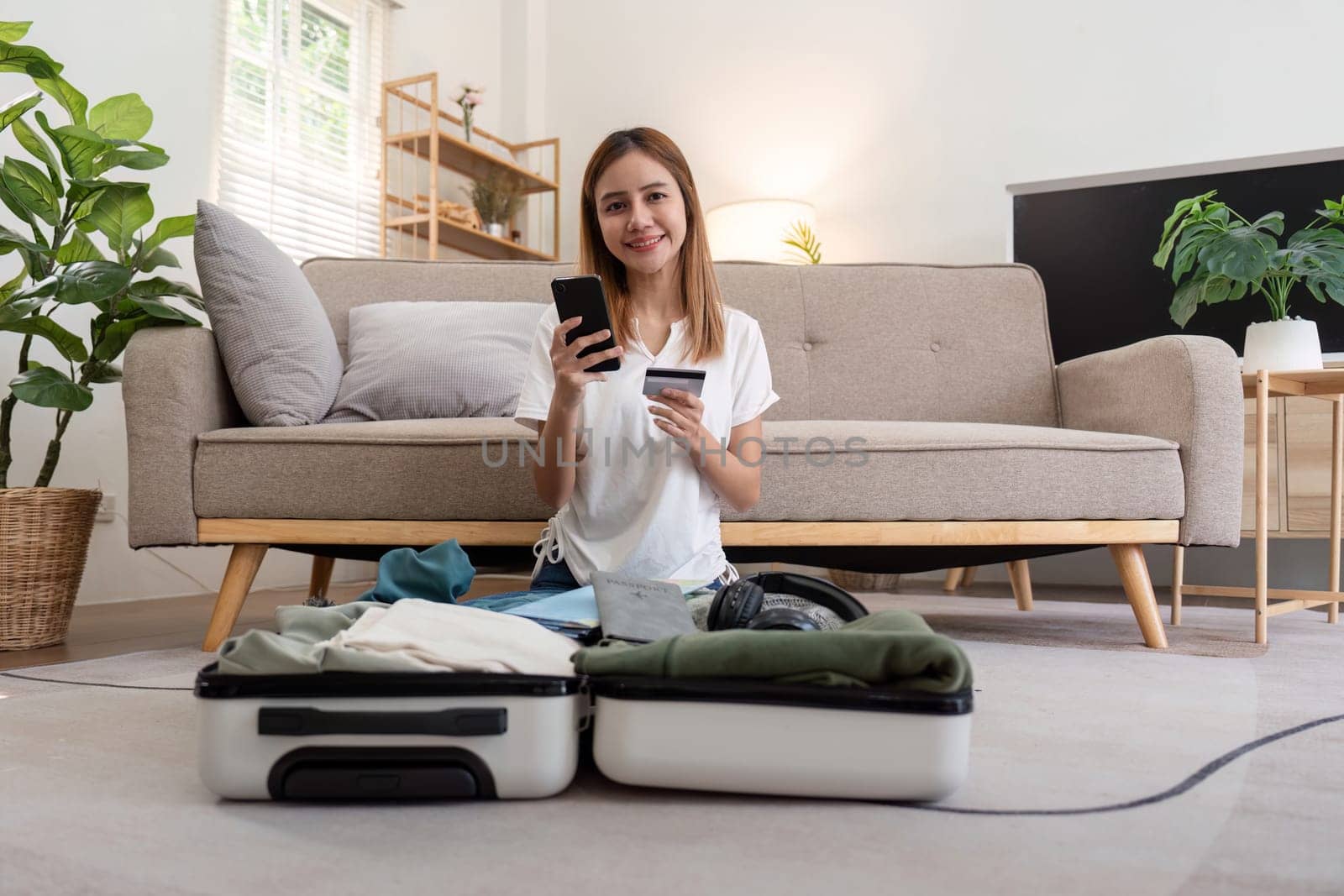 Asian woman using credit card booking flight tickets and hotel at home. Planning a trip and online booking, Summer vacation concept.