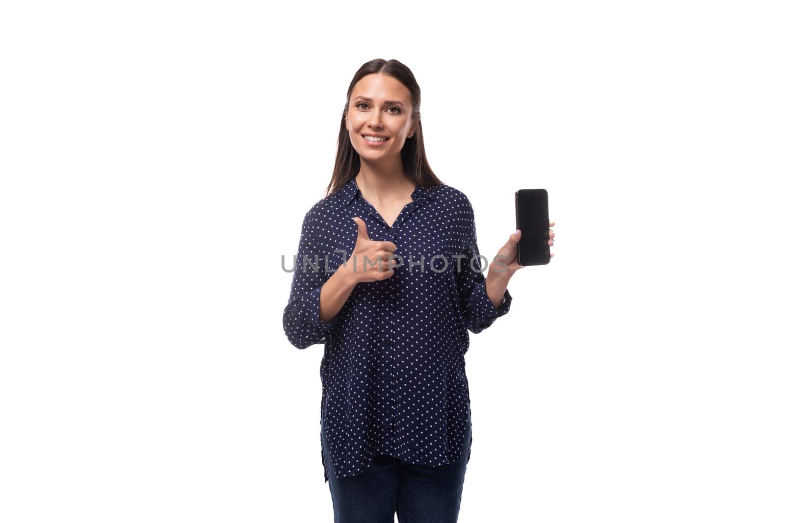 young european slender brunette woman in blue clothes advertises a smartphone with a mockup for advertising.