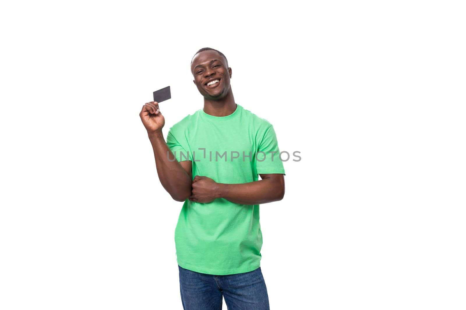A 30-year-old American man dressed in a light green basic T-shirt holds a plastic credit card.