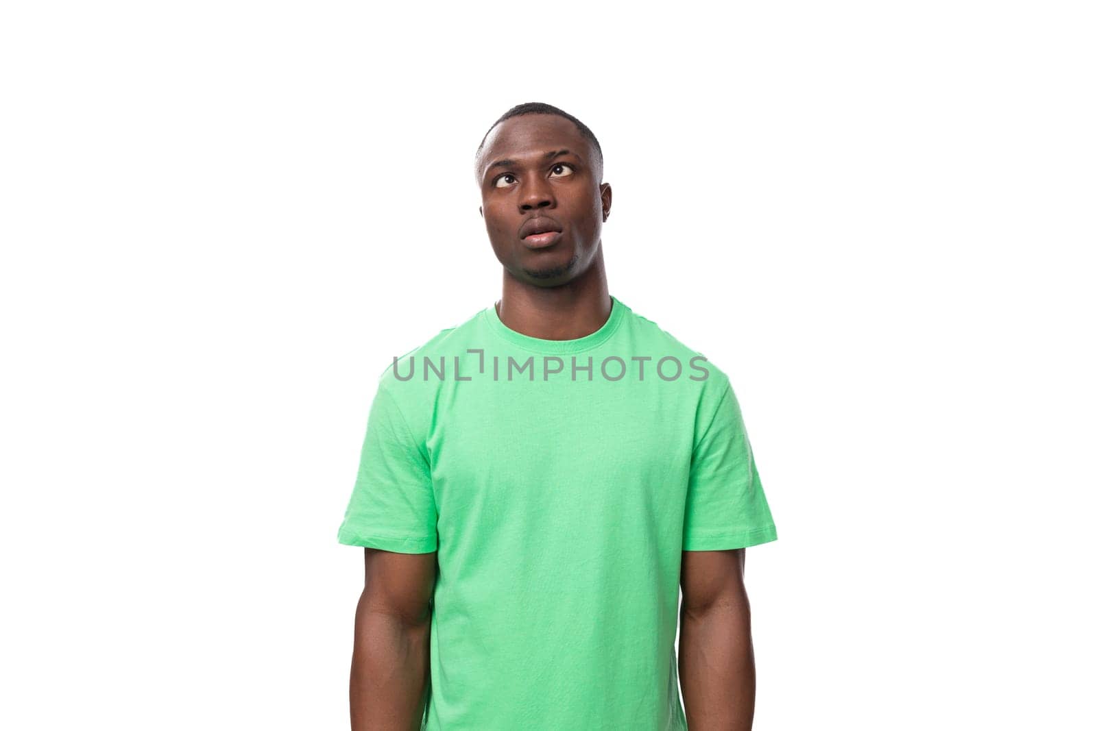 A 30-year-old smart African man dressed in a light green T-shirt is trying to remember a thought.
