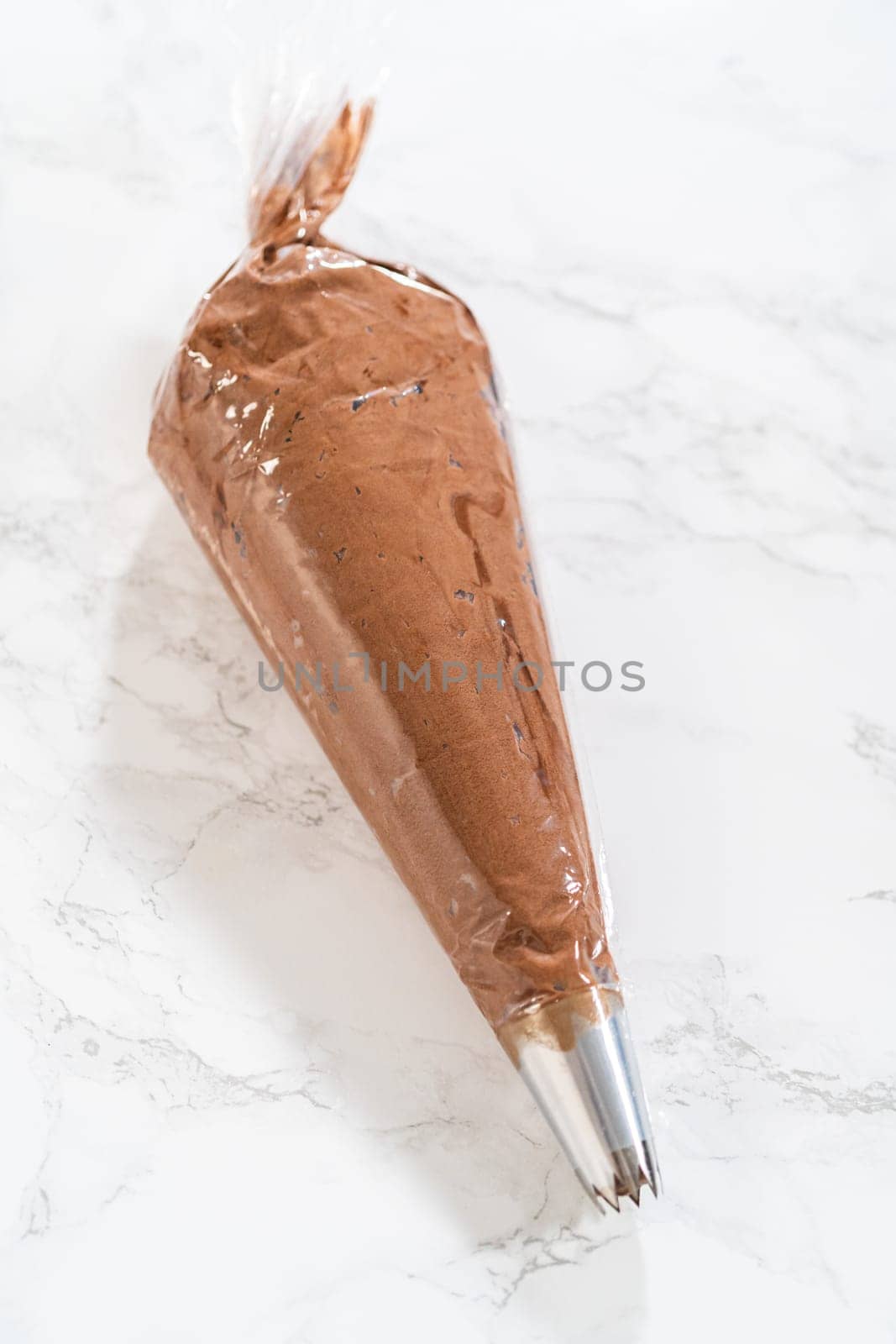 The chocolate icing is carefully transferred into a piping bag, ready to adorn the scrumptious cupcakes.