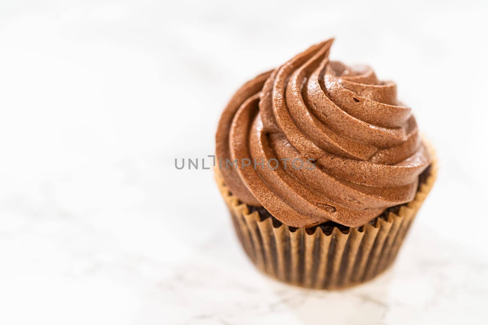 A single, indulgent chocolate cupcake sits gracefully on the kitchen counter, tempting your taste buds.