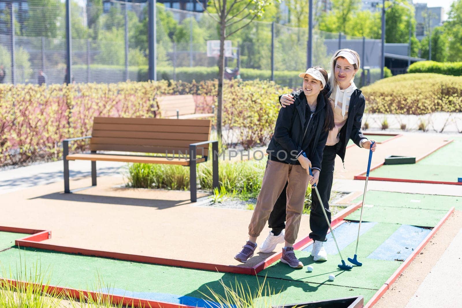 mother and daughter playing mini golf, children enjoying summer vacation by Andelov13
