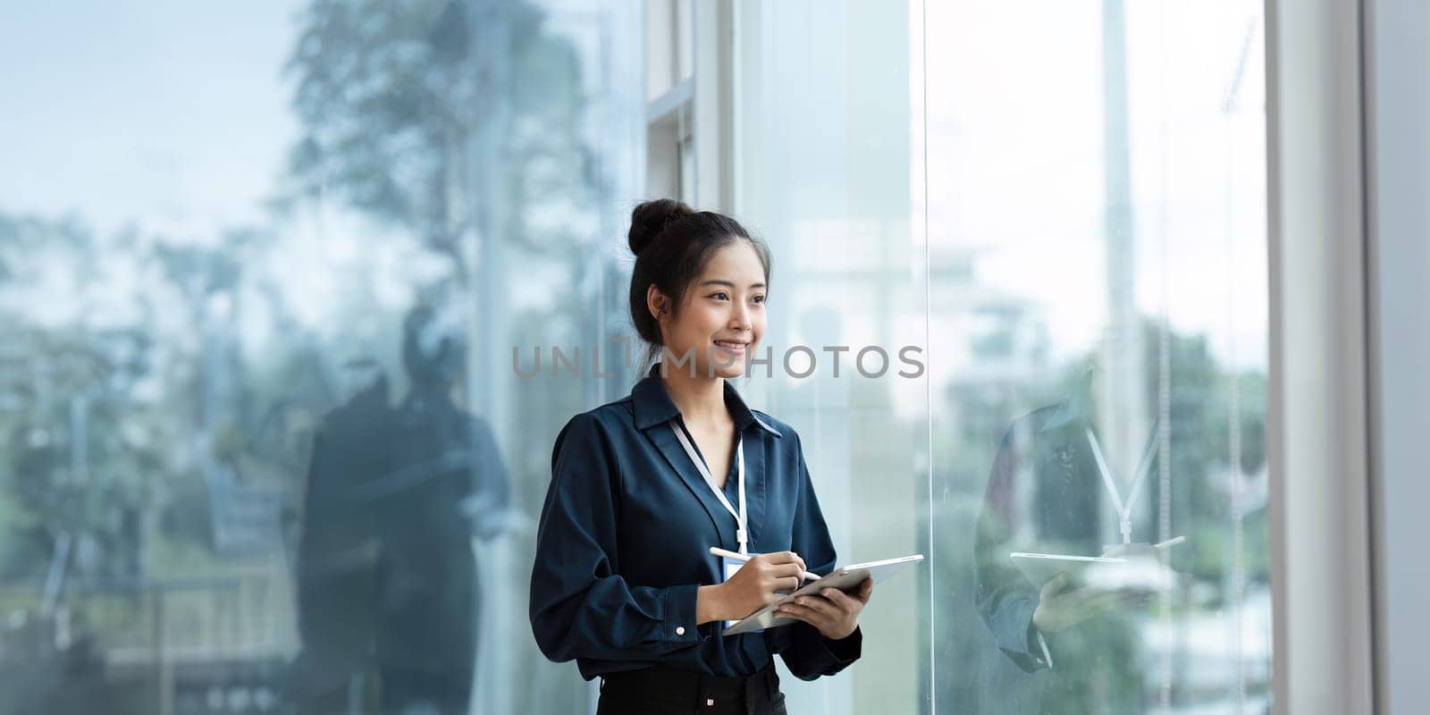 happy professional business woman working on tablet at work standing near window.