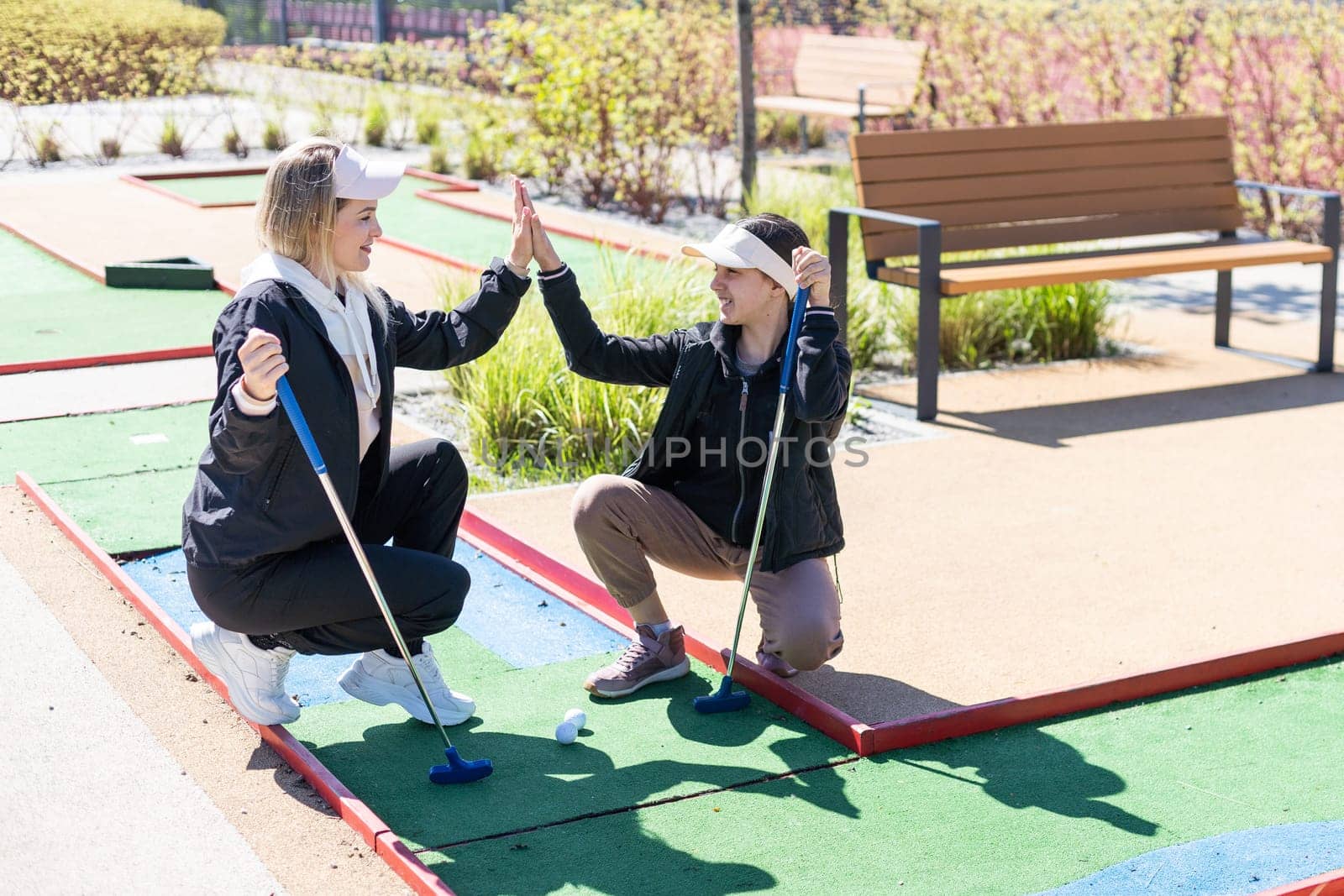 mother and daughter playing mini golf, children enjoying summer vacation. High quality photo