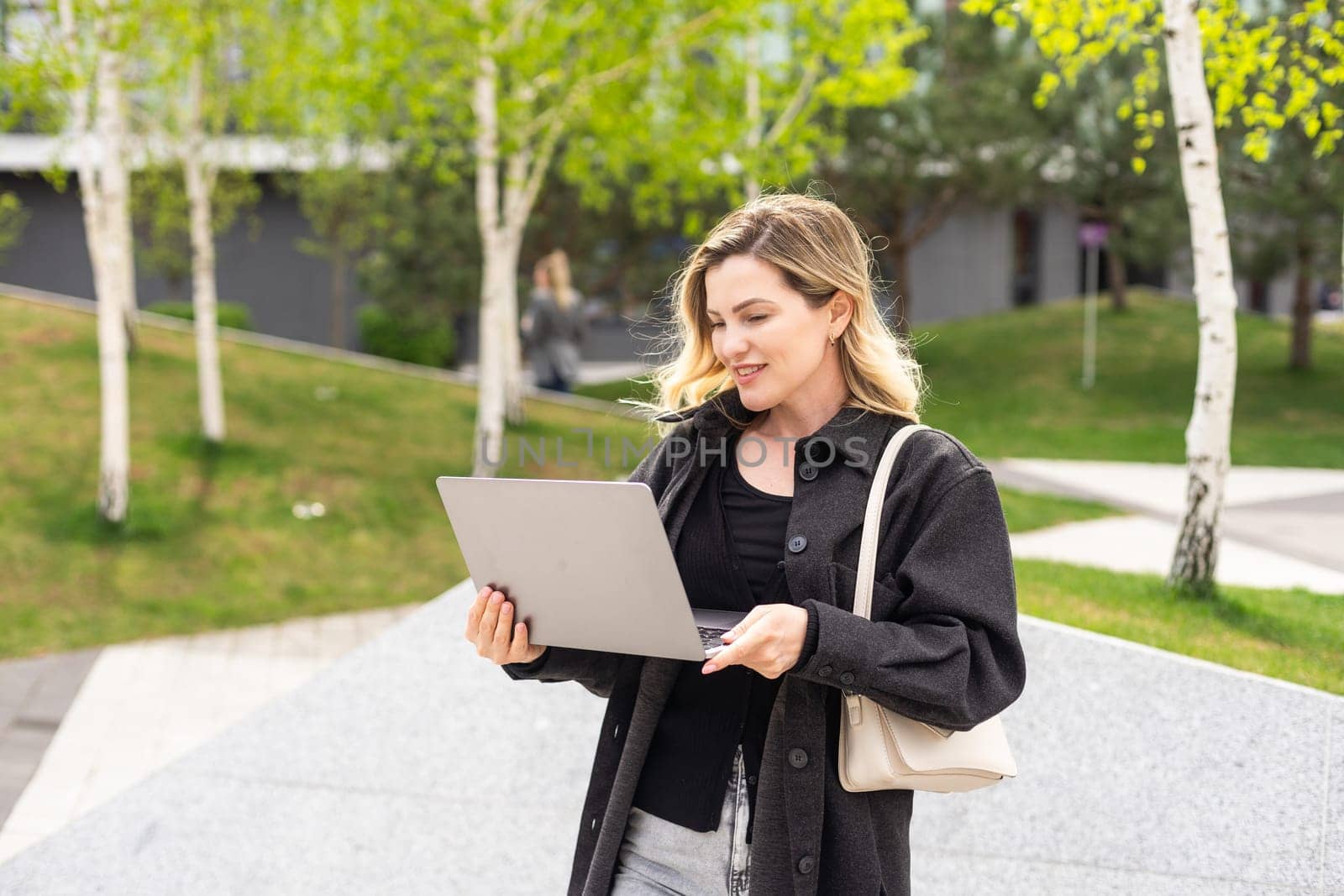 Young beautiful business woman sitting on a bench in the sunny city. High quality photo