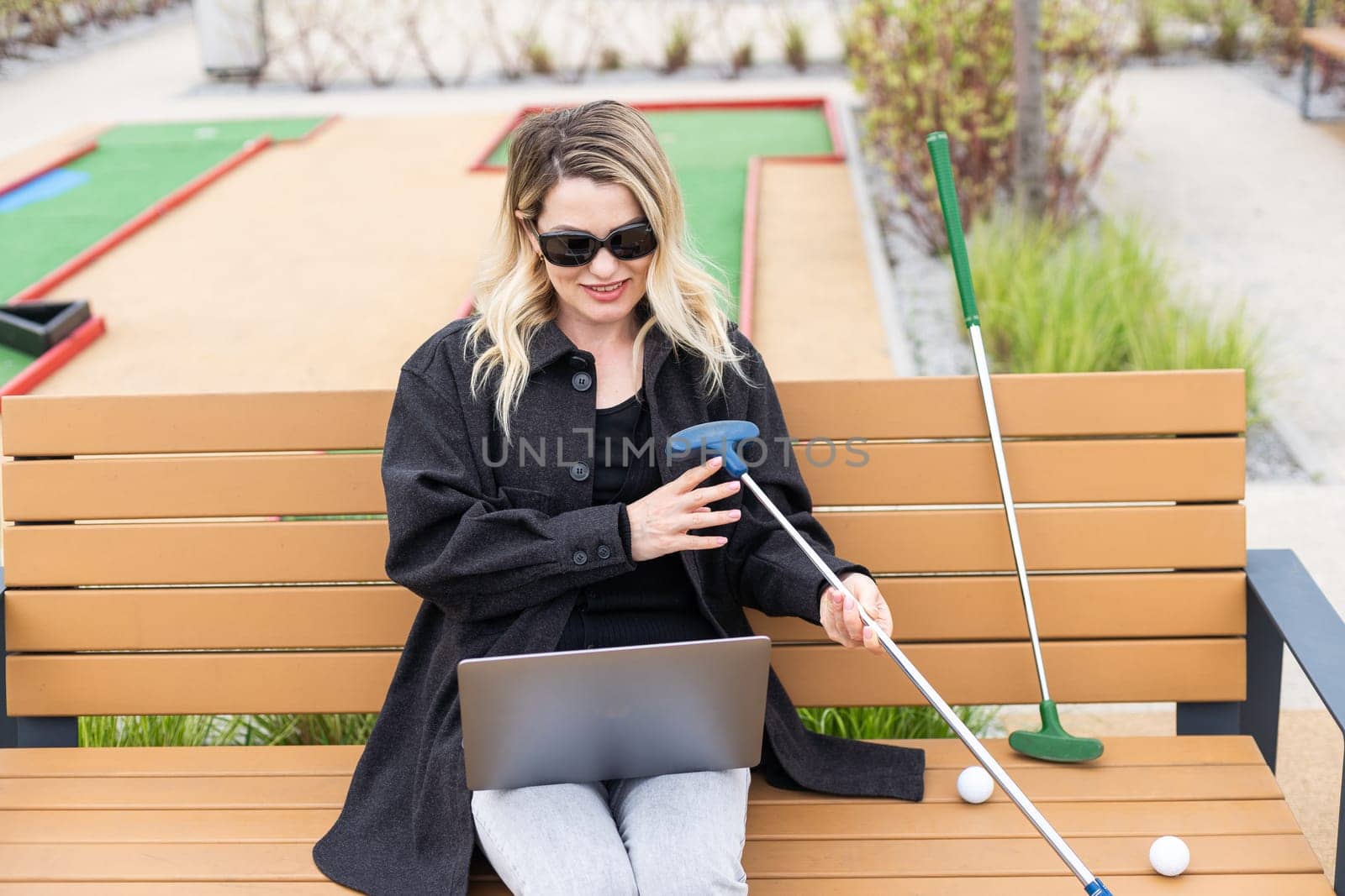 A businesswoman using a laptop on a golf course. High quality photo