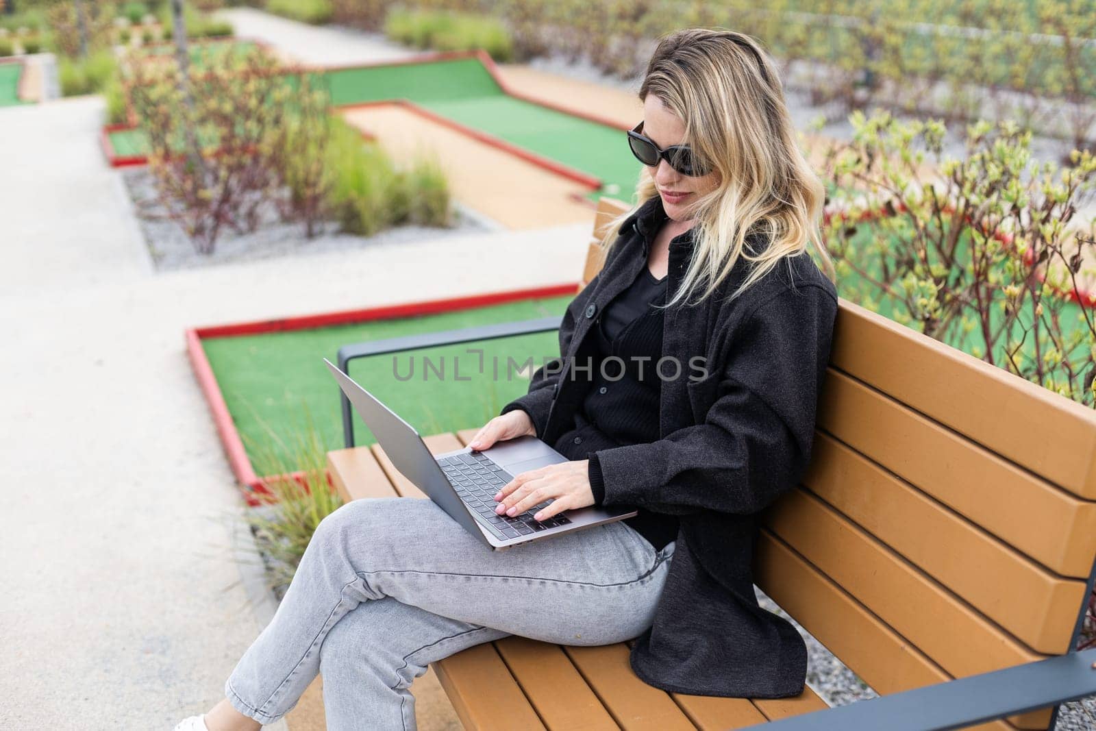 A businesswoman using a laptop on a golf course. High quality photo