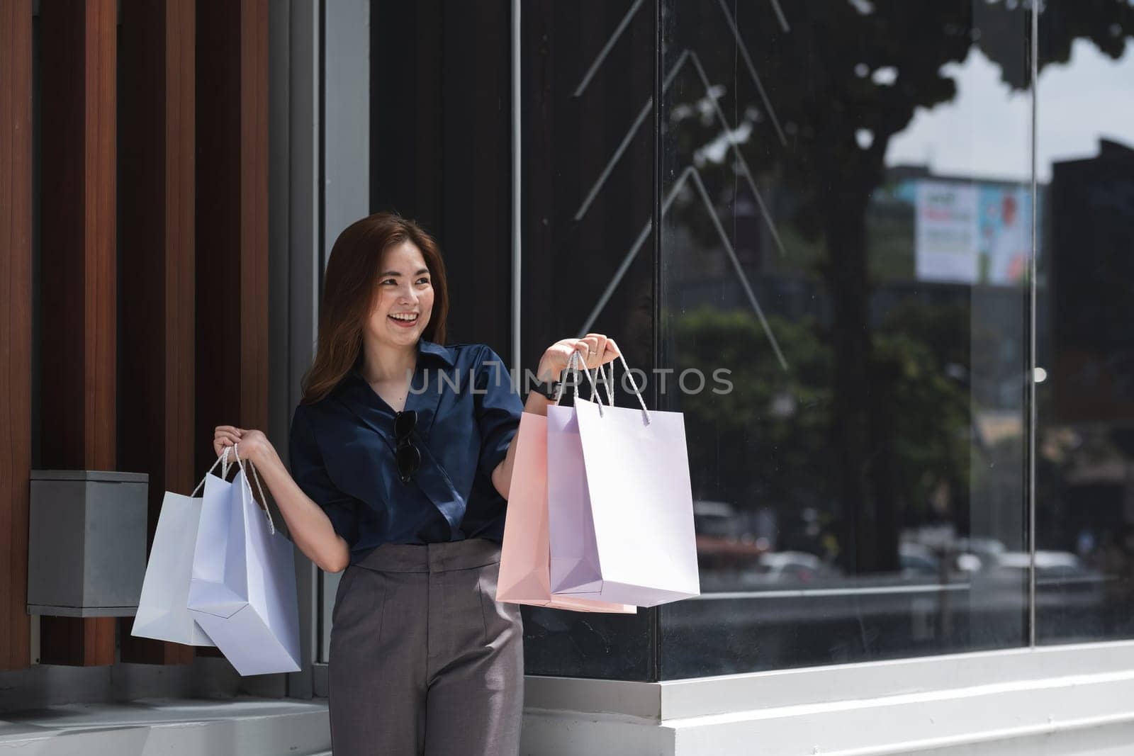A woman is holding two shopping bags and smiling.
