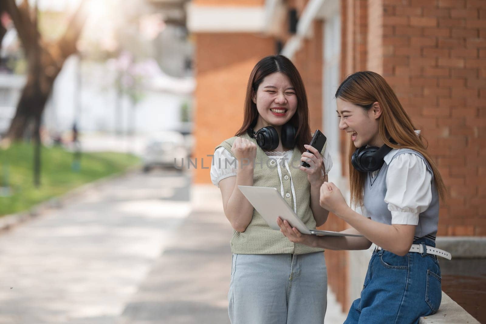 Beautiful young Asian woman college student with friends at outdoors. College student working on the college campus by wichayada