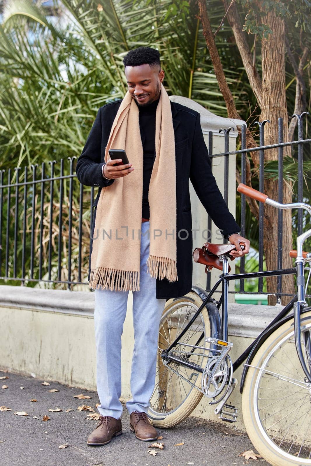 Happy, black man and smartphone with bicycle in city for eco friendly transportation and online on social media. Person, mobile phone and search for reviews or destinations for tours on vacation. by YuriArcurs