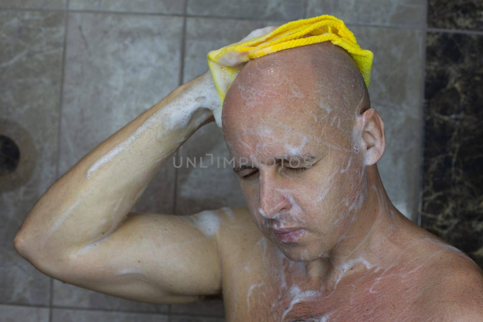 Bald European man washes his head in the shower by timurmalazoniia