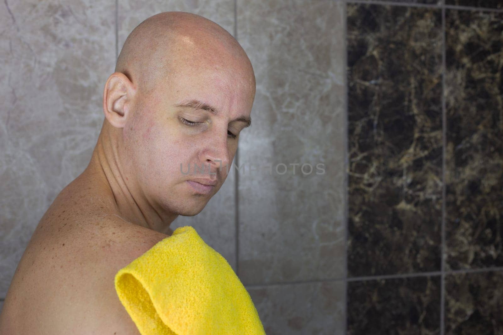 Man rubs his shoulder with washcloth in the shower, care and hygiene of body and skin at home