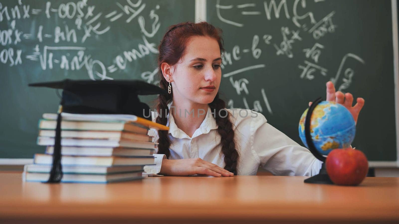 A red-haired high school senior poses against a backdrop of books, a globe and a graduation cap. by DovidPro