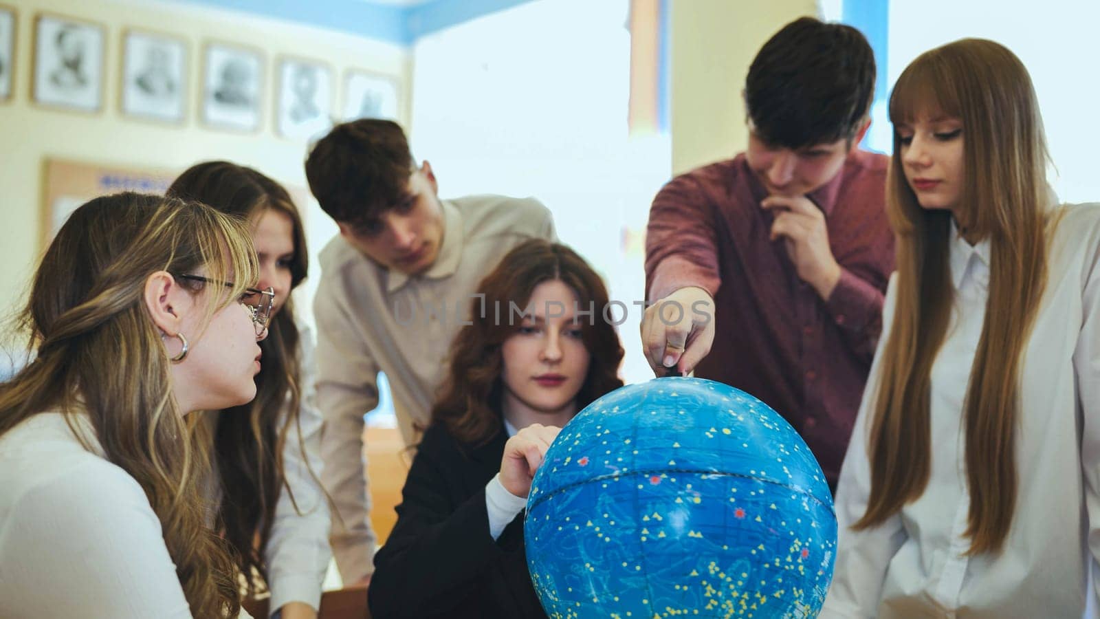 Students look at a globe of the starry sky in a classroom at school. by DovidPro