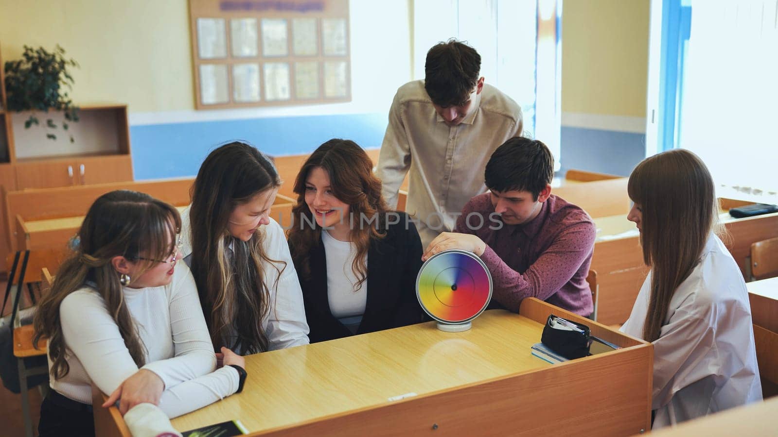 Students in physics class spin Newton's colorful wheel. by DovidPro