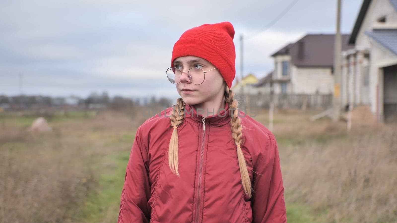 A sad teenage girl in red clothes is walking down the street. by DovidPro