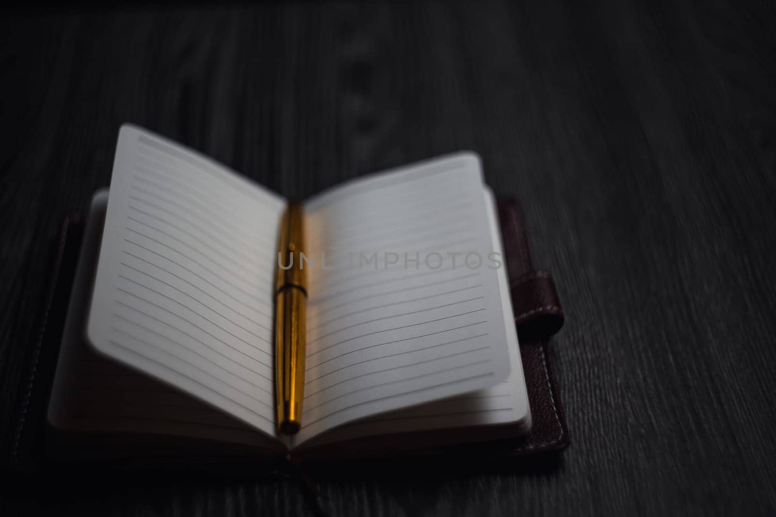 Subject shooting - Notepad and gold pen. Blank notepad on a darck wood. High quality photo