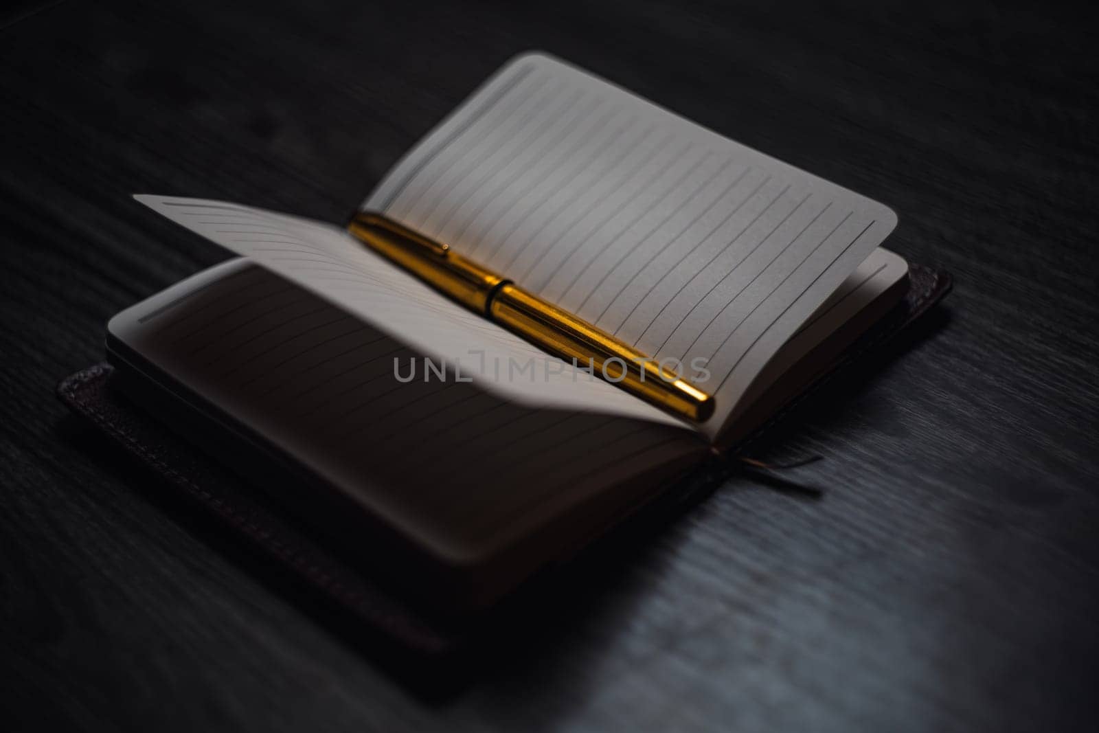 Subject shooting - Notepad and gold pen. Blank notepad on a darck wood. High quality photo