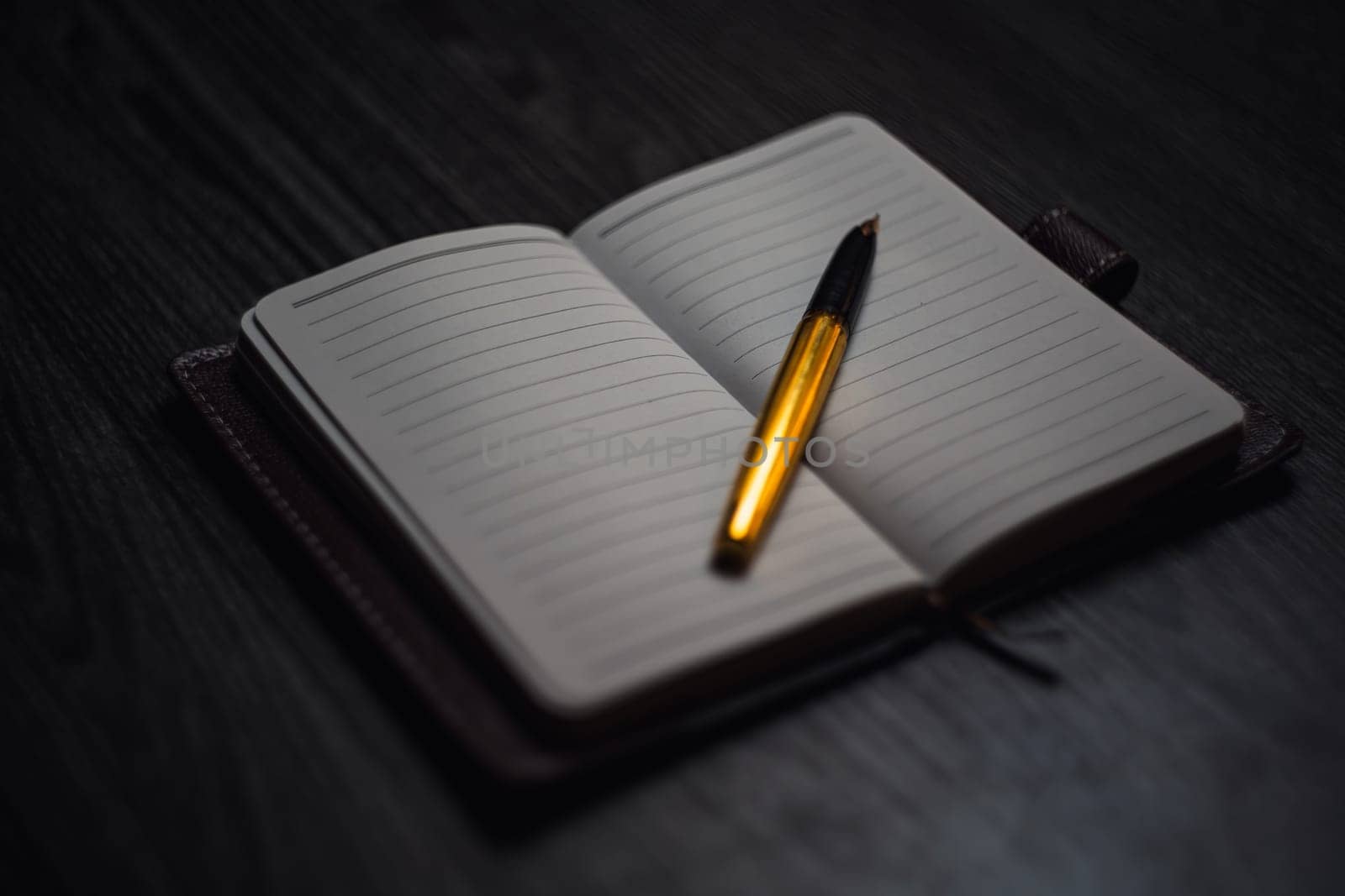 Subject shooting - Notepad and gold pen. Blank notepad on a darck wood. High quality photo