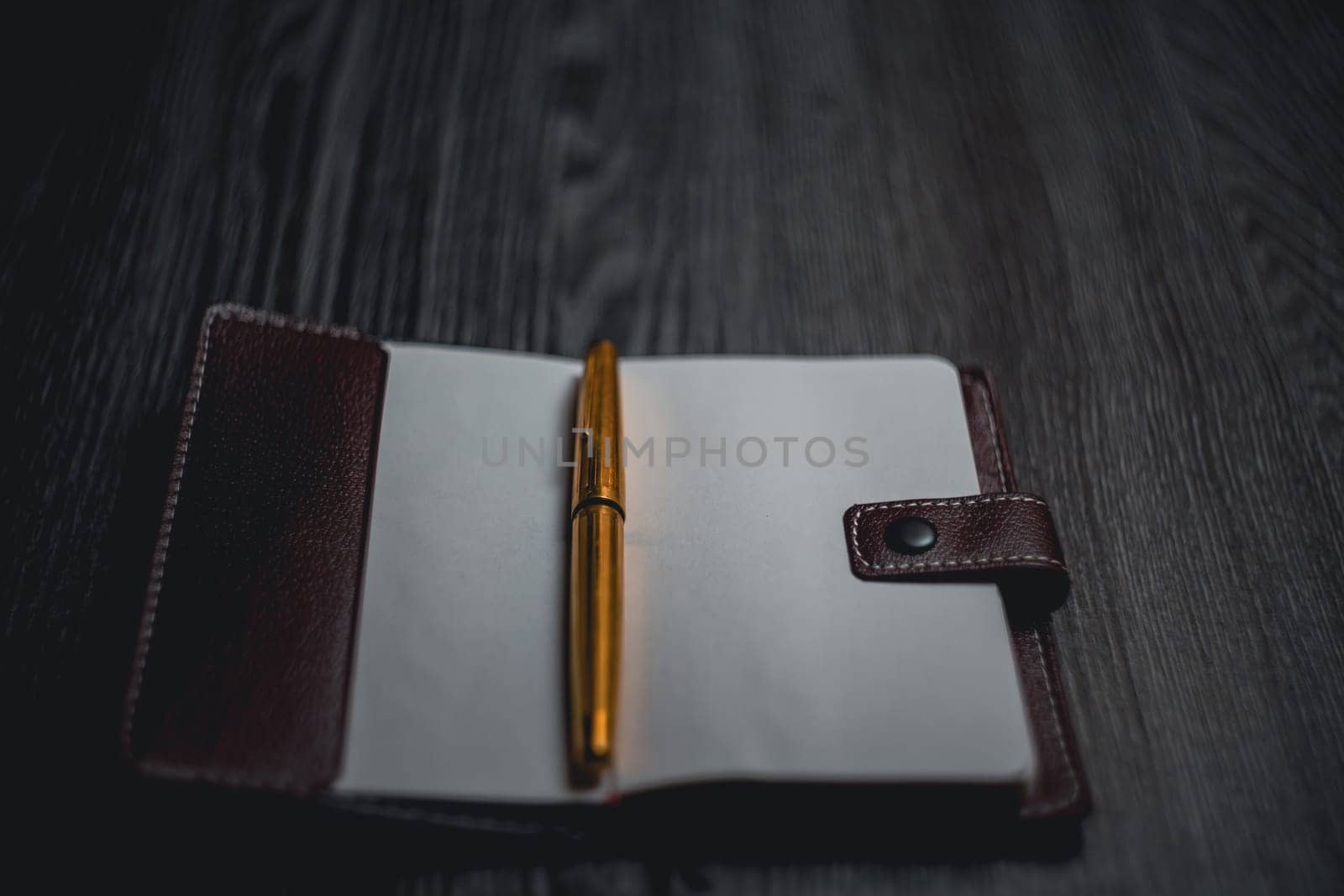 Subject shooting - Notepad and gold pen. Blank notepad on a darck wood. High quality photo