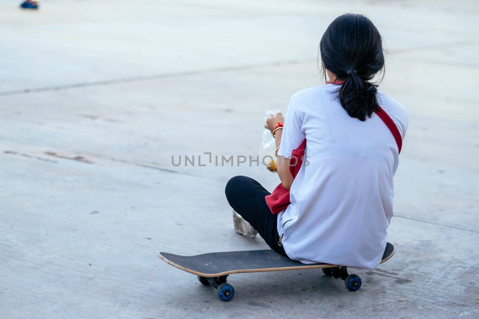 Girl sitting on her back on a skateboard in the city. Outdoors, lifestyle