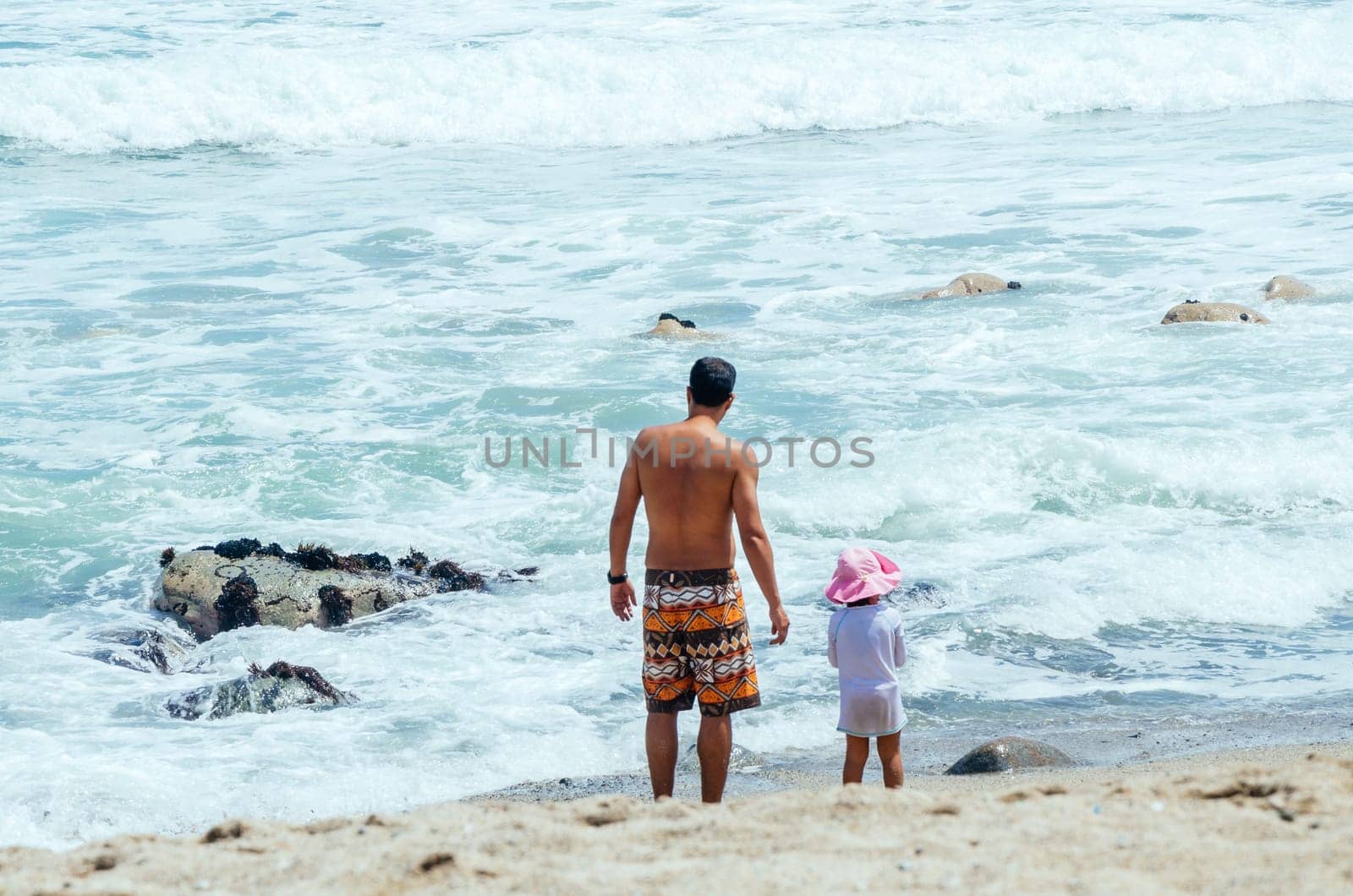 father and son walking at the edge of the sea. by Peruphotoart