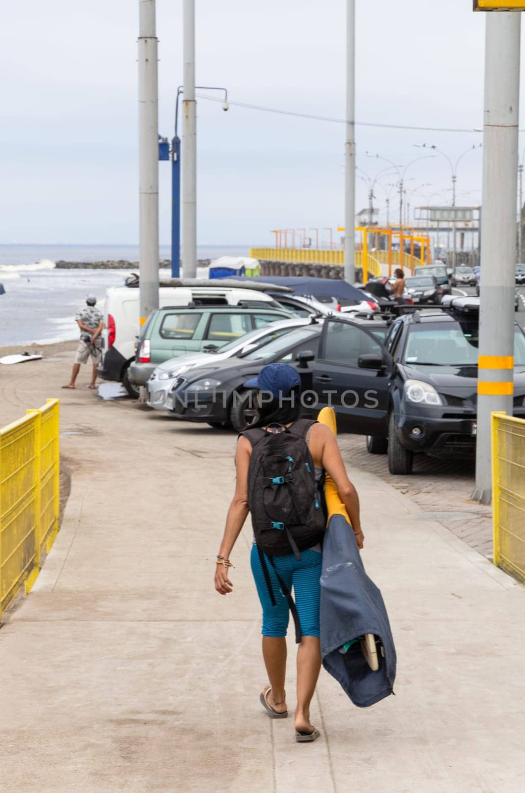 Young female surfer walking towards the ocean carrying a board