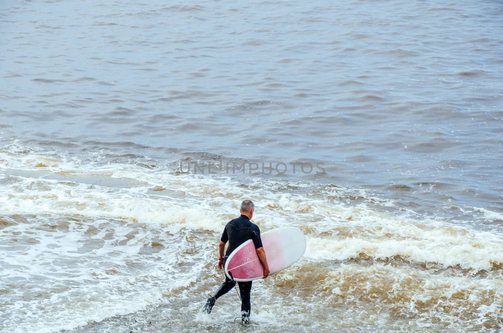 Surfer. Surfer man with surfboard walking into the sea. Healthy lifestyle, water activities, water sports