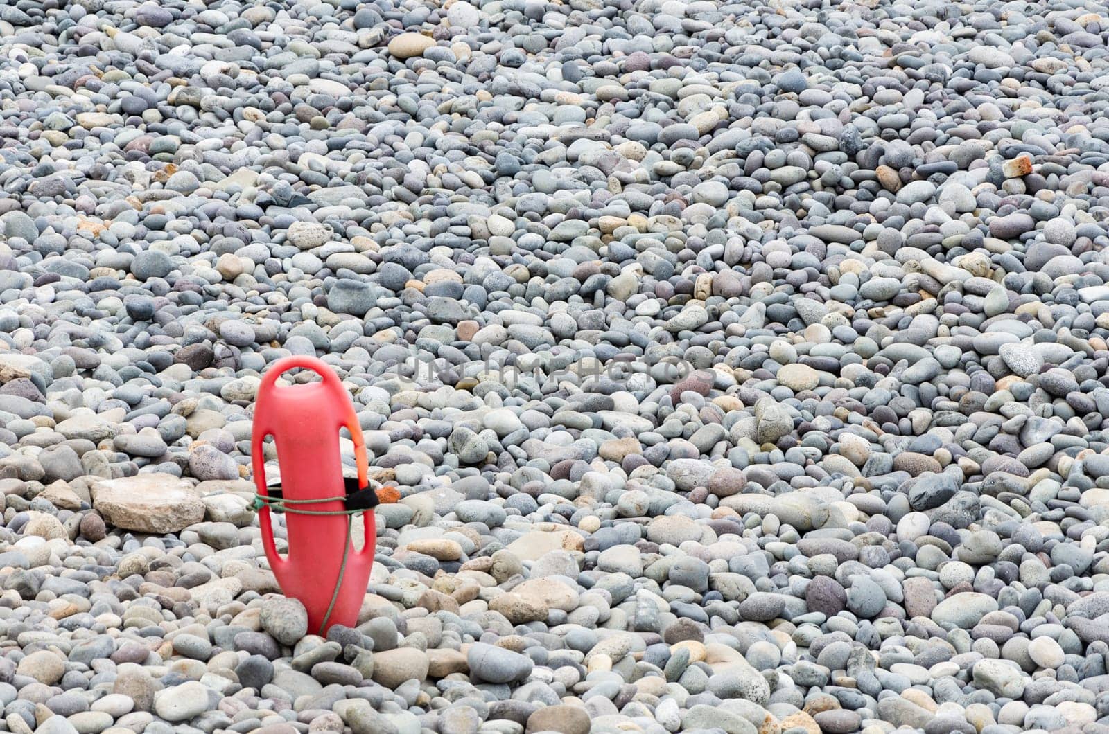 Red plastic buoyancy aid in the sand on lonely beach. by Peruphotoart