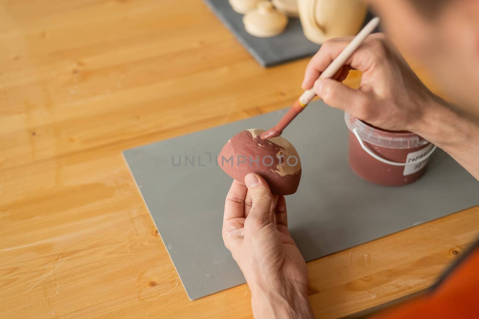 Close-up of a potter's hands with a brush painting ceramic dishes