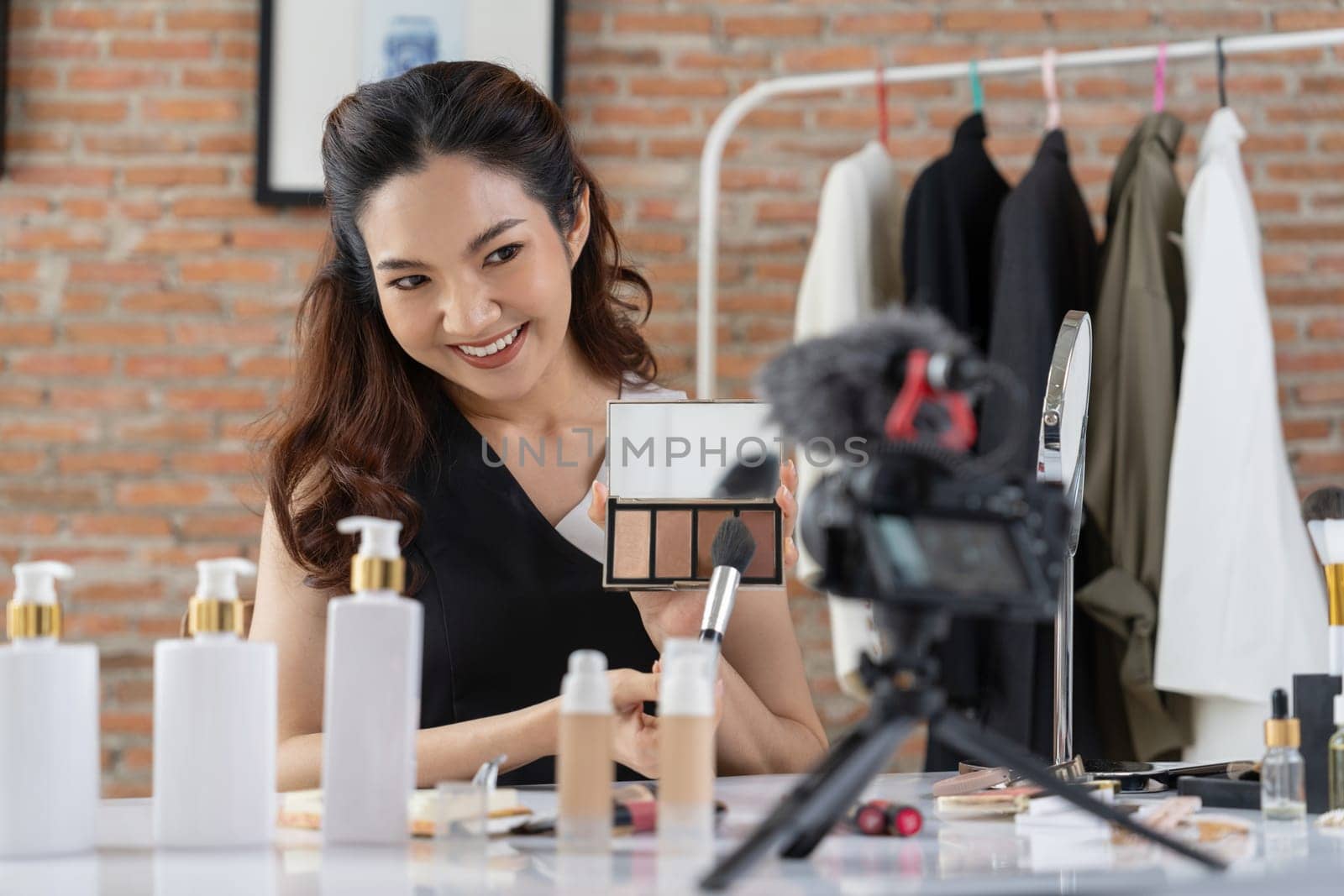 Woman influencer shoot live streaming vlog video review makeup uttermost social media or blog. Happy young girl with cosmetics studio lighting for marketing recording session broadcasting online.