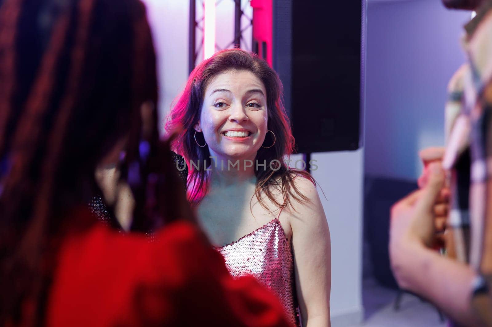 Smiling cheerful woman partying with friends and socializing at nightclub discotheque. Carefree happy girl clubbing and attending disco social gathering event, enjoying nightlife leisure