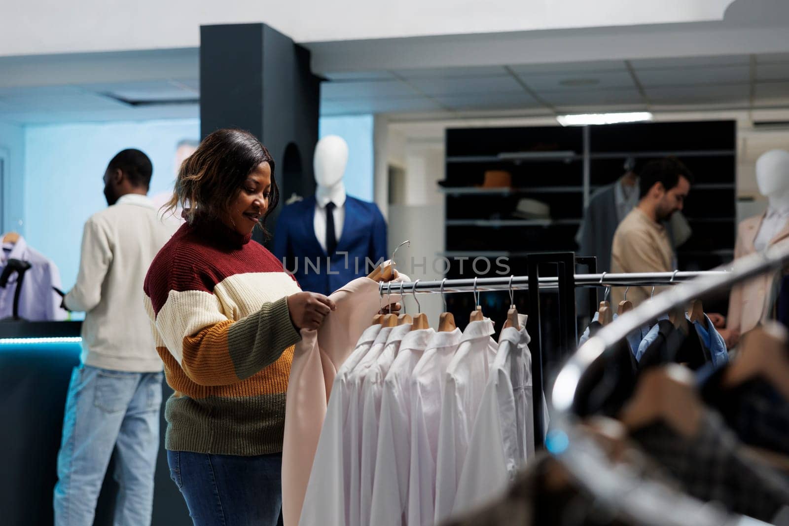 Woman holding jacket on hanger in store by DCStudio