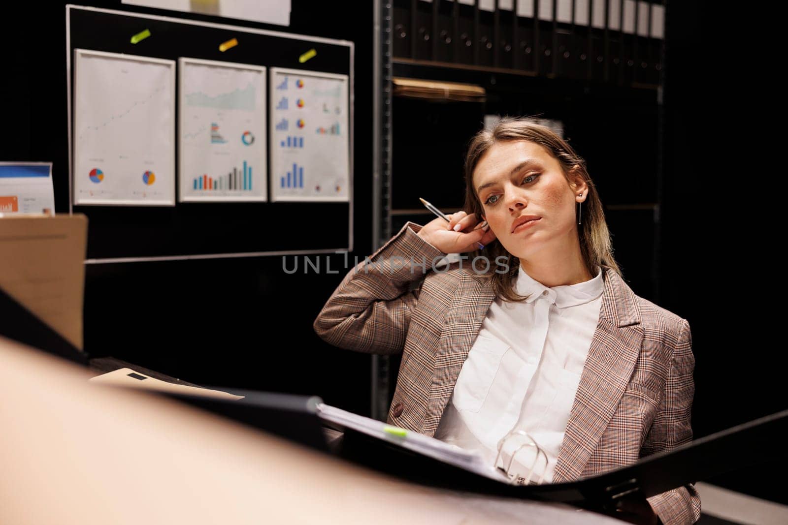 Private detective analyzing crime scene report, searching for new clues to catch mysterious suspect in arhive room. Police officer working overtime at criminal case, reading criminology files