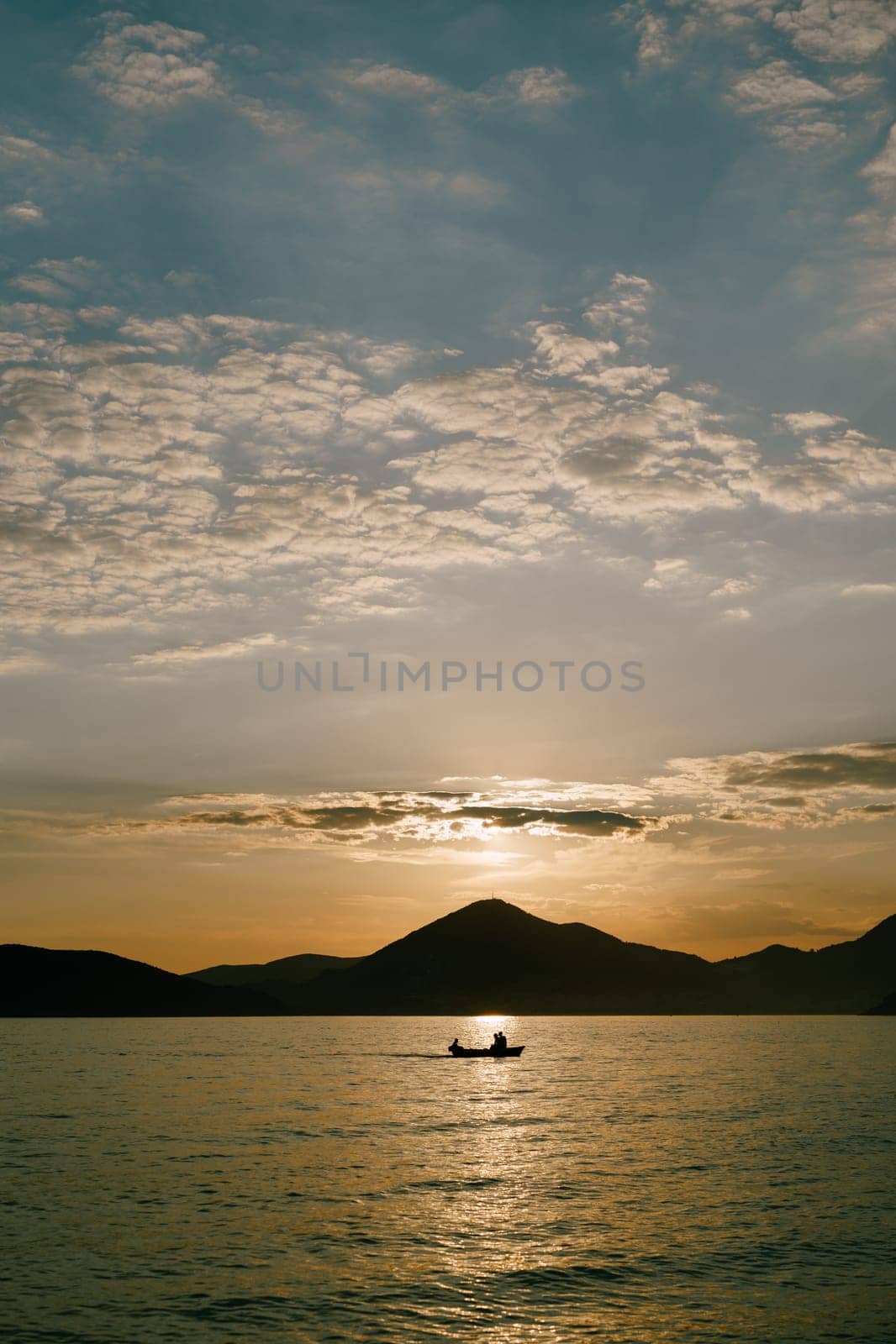 Sailing yacht sails on the sea against the backdrop of mountains at sunset. High quality photo