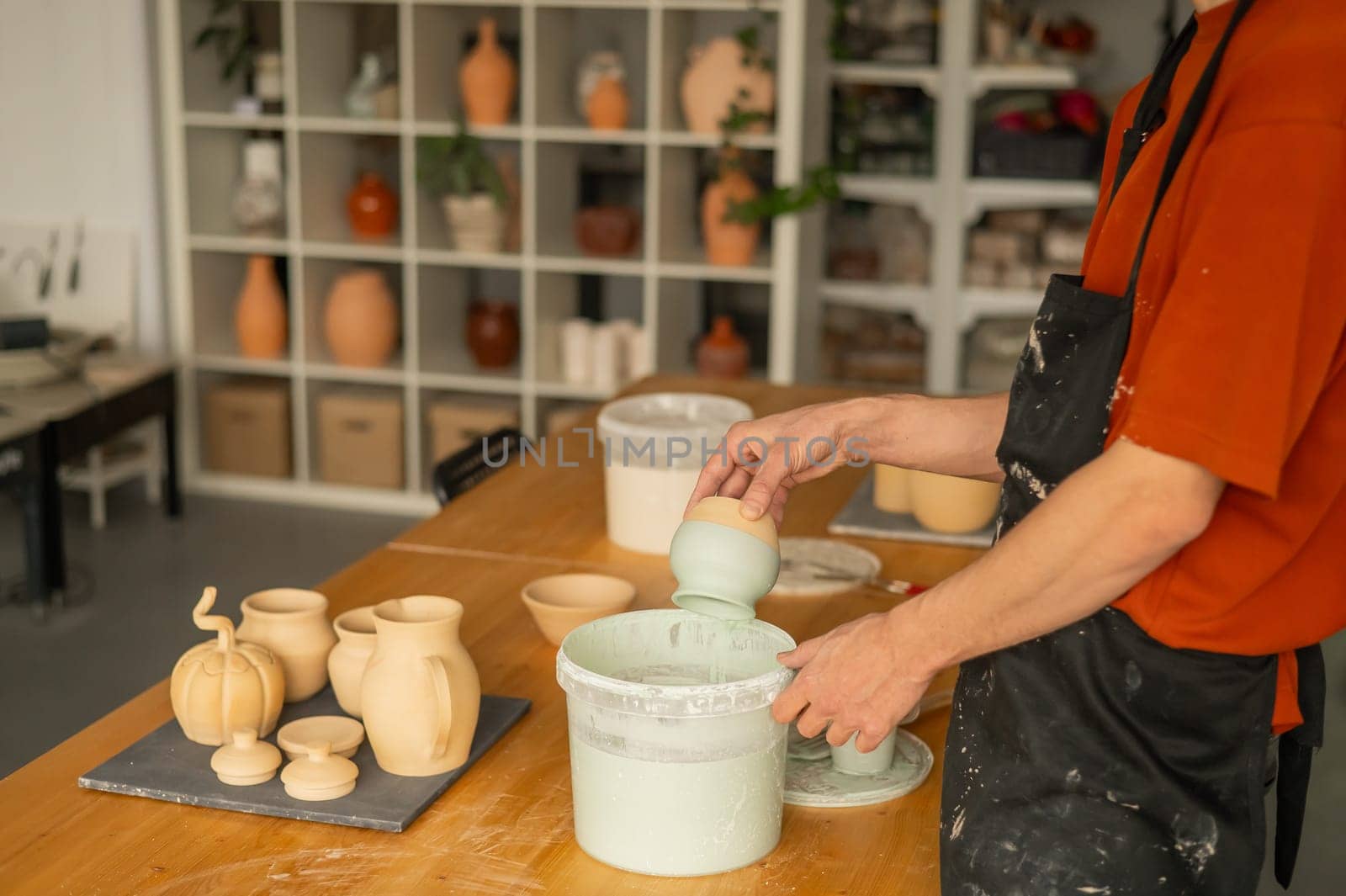 Close-up of a potter's hands glazing a pottery piece. by mrwed54