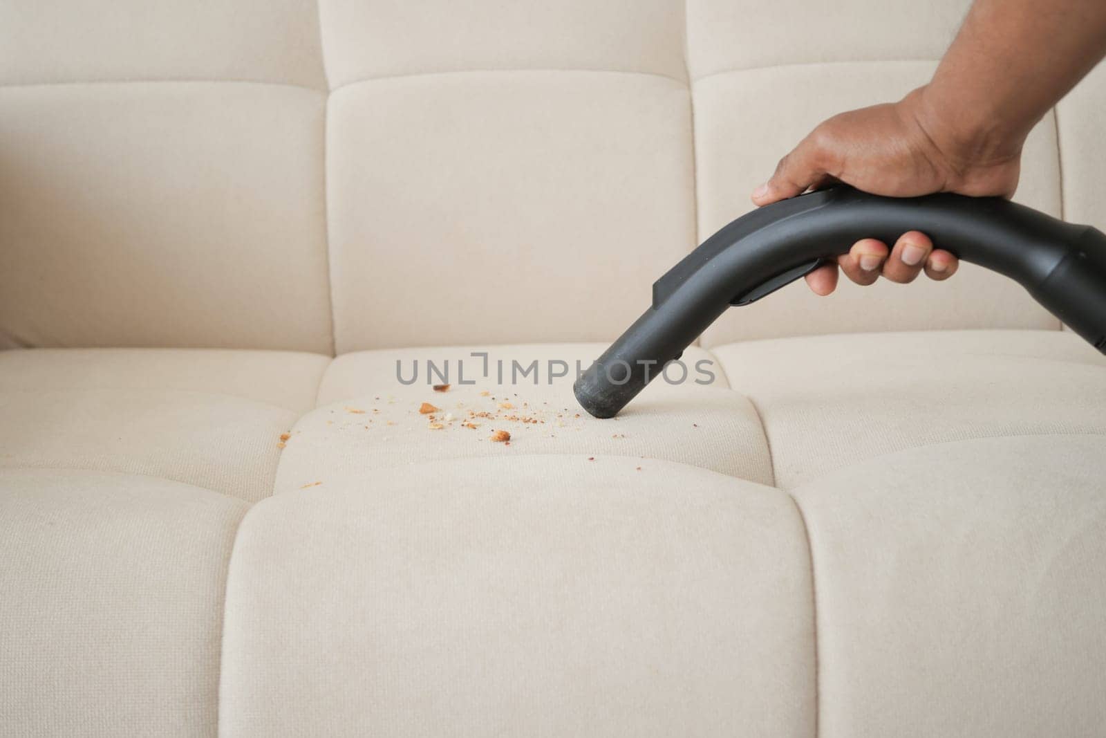 Cleaning Sofa with Vacuum Cleaner in living room.