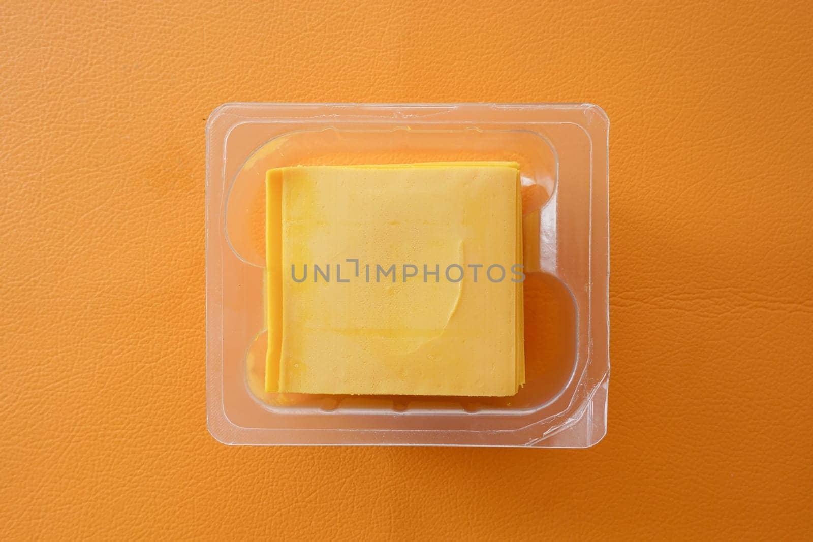 slices of cheese in the package on orange background.